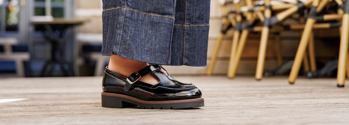 Femme portant une paire de babies en cuir vernis noir avec jeans large en centre ville