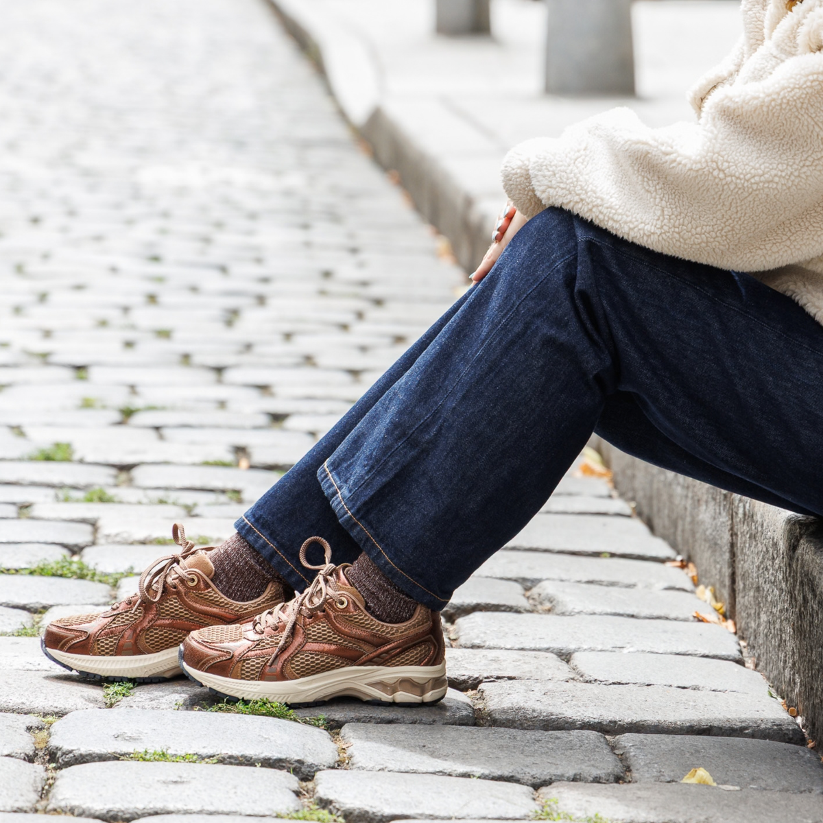 Femme portant une paire de baskets, assise sur un pavé