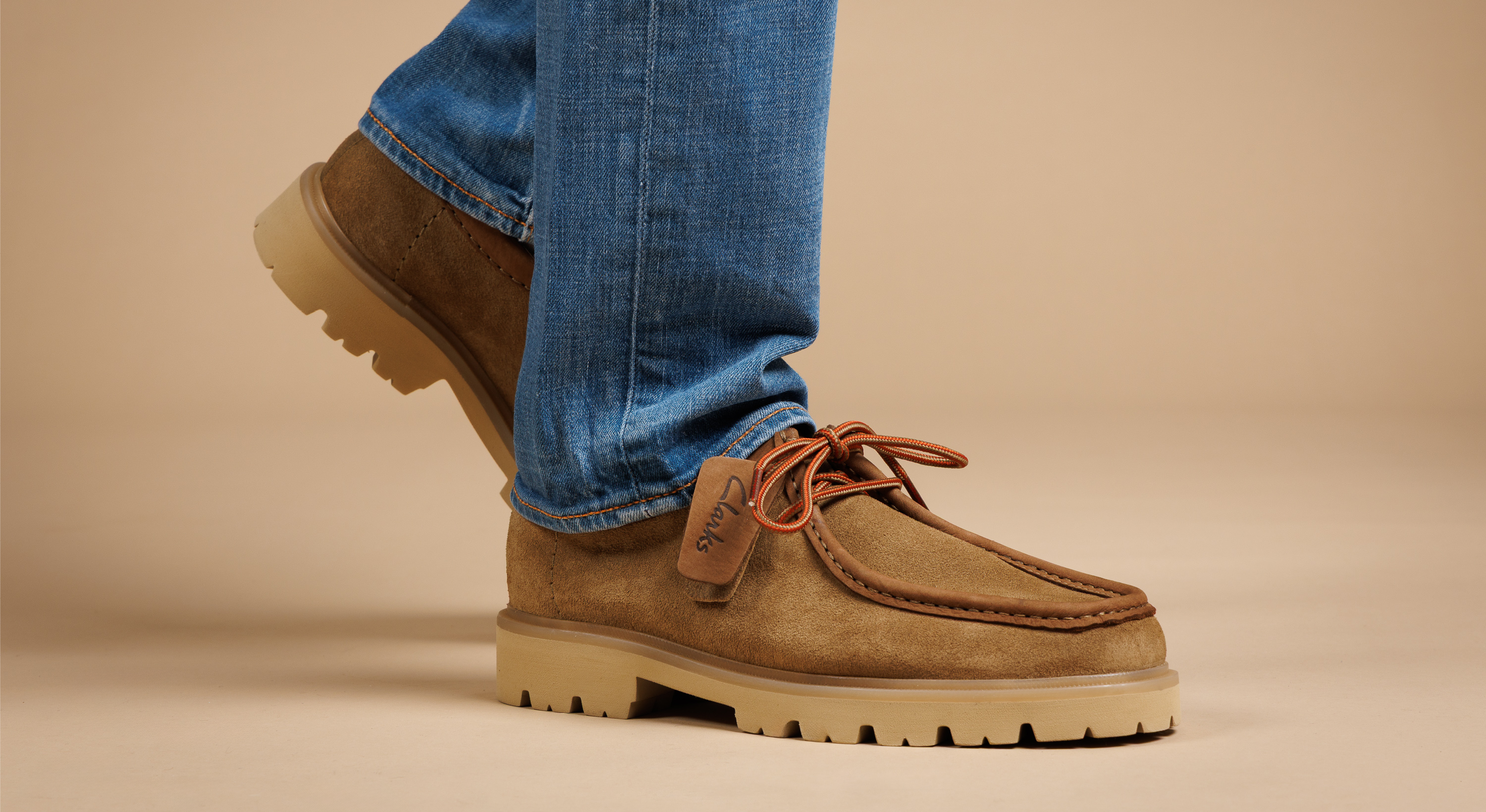Image  paire de derbies clarks portées par un Homme sur fond beige 